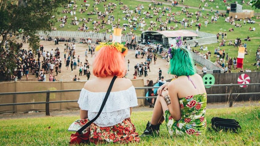 Two female Splendour punters sitting on the hill overlooking the North Byron Parklands Amphitheatre