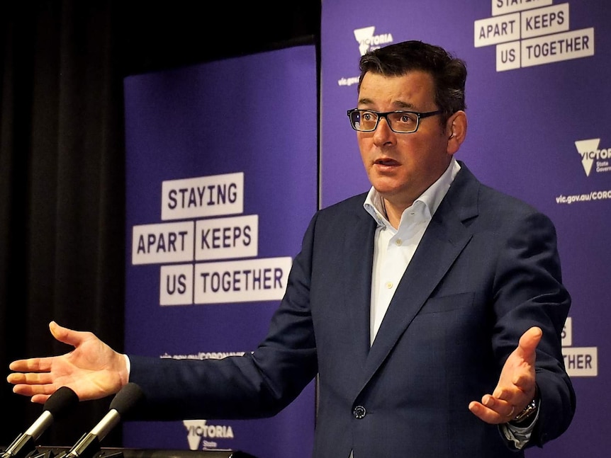 Daniel Andrews at a press conference standing with his arms spread wide.