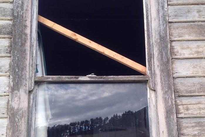 A broken window partially boarded up in an out building at Mt Baines, Tasmania.