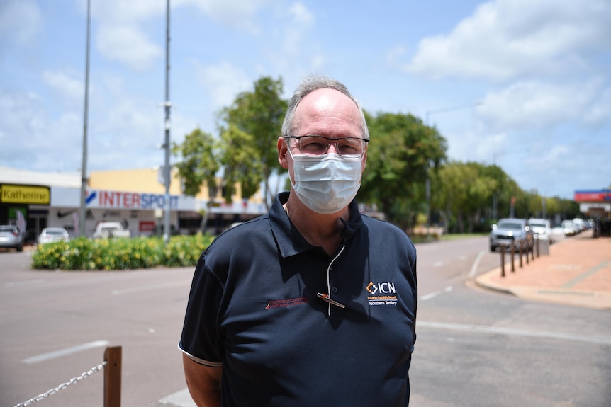 a man wearing a face mask and a navy collared top