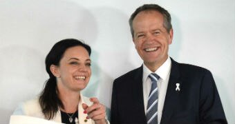 Bill Shorten and Emma Husar smile next to each other holding up a placard