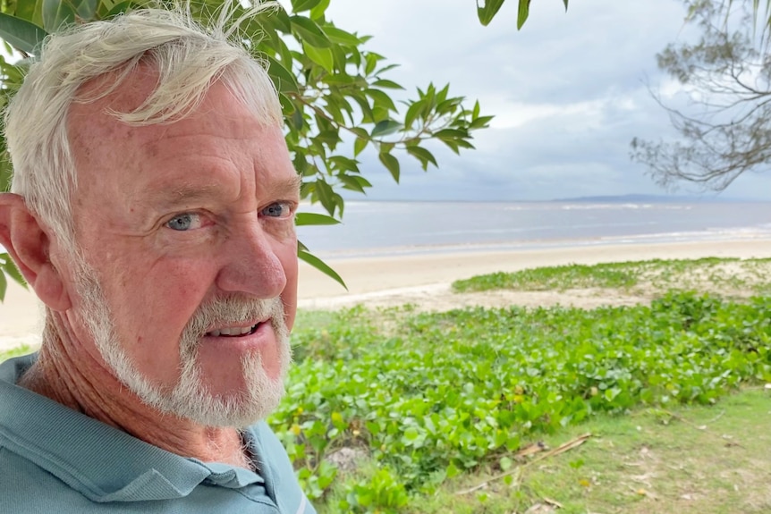 Close up of man with grey hair with beach in background