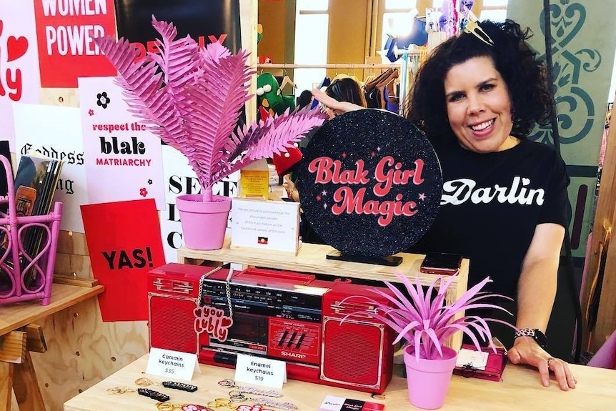 Woman poses behind a counter with her merchandise