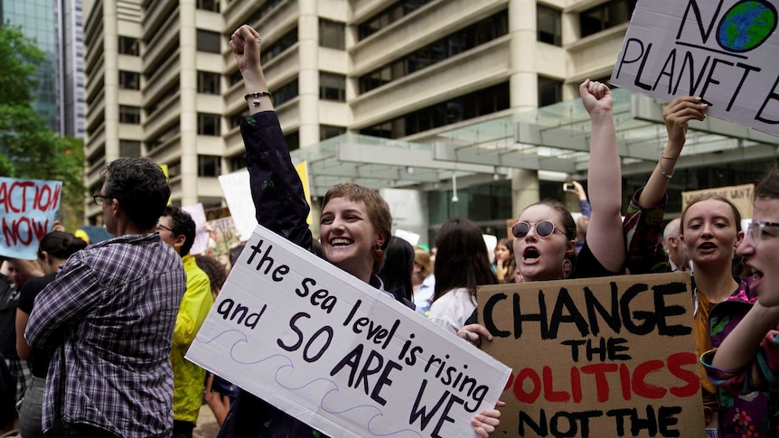 People holding signs and raising their arms in the air.