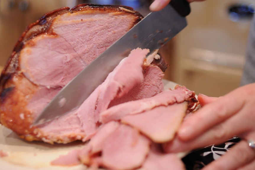 A knife carving a Christmas ham
