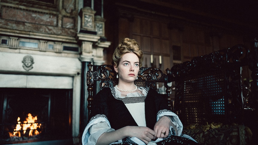 Emma Stone seated in 2018 film The Favourite.