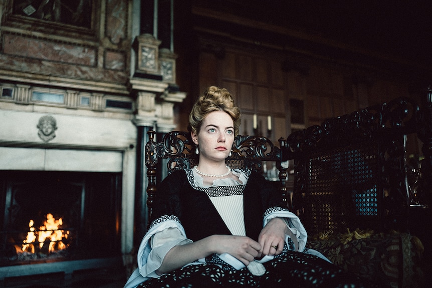 Colour still of Emma Stone seated in 2018 film The Favourite.