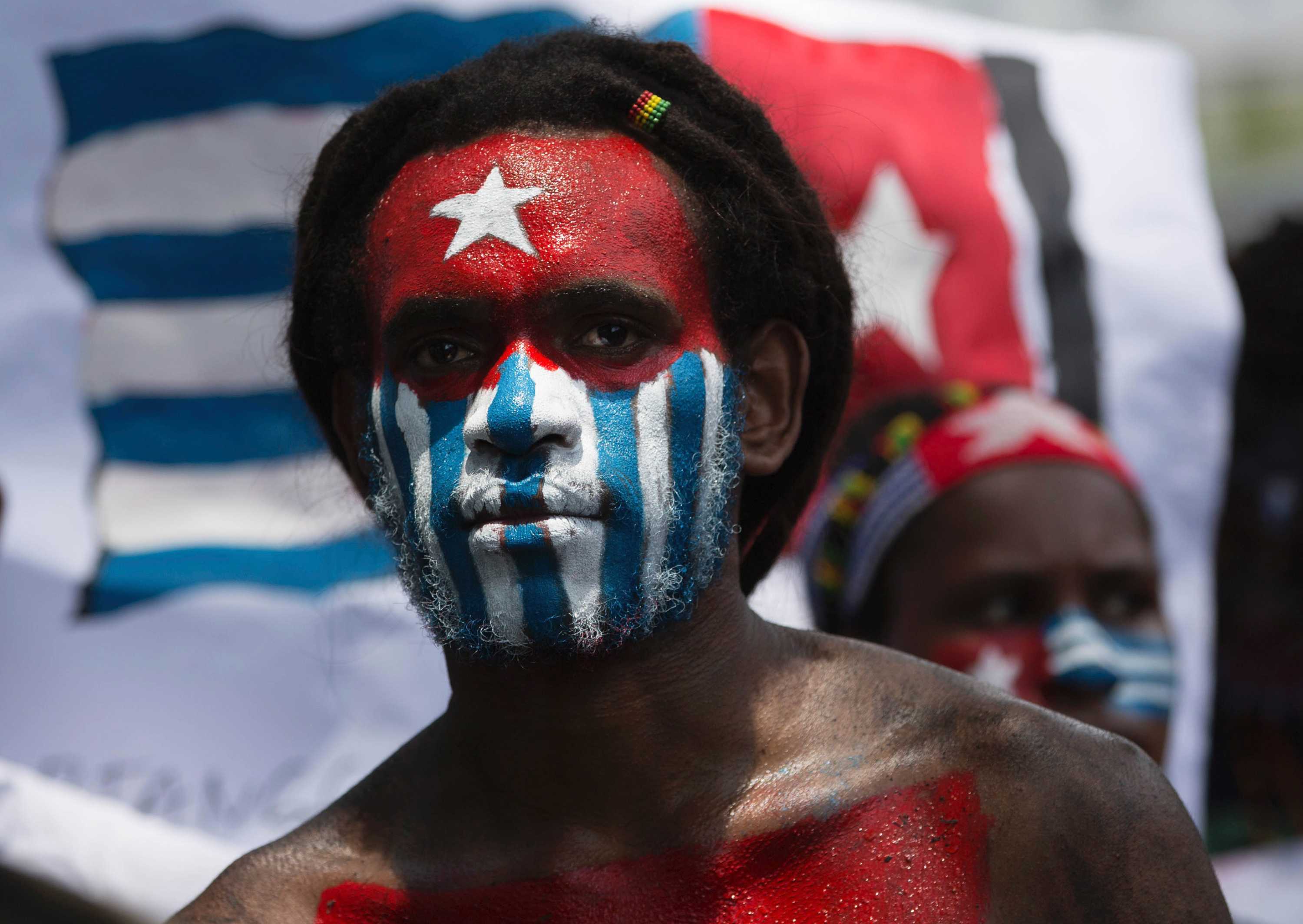 A Papuan student looks at the camera with his body and face painted with the colors of the banned separatist flag.