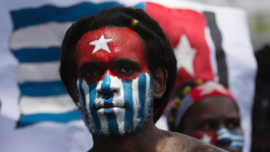 A Papuan student looks at the camera with his body and face painted with the colors of the banned separatist flag.