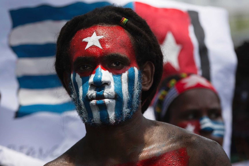 A Papuan student looks at the camera with his body and face painted with the colors of the banned separatist flag.