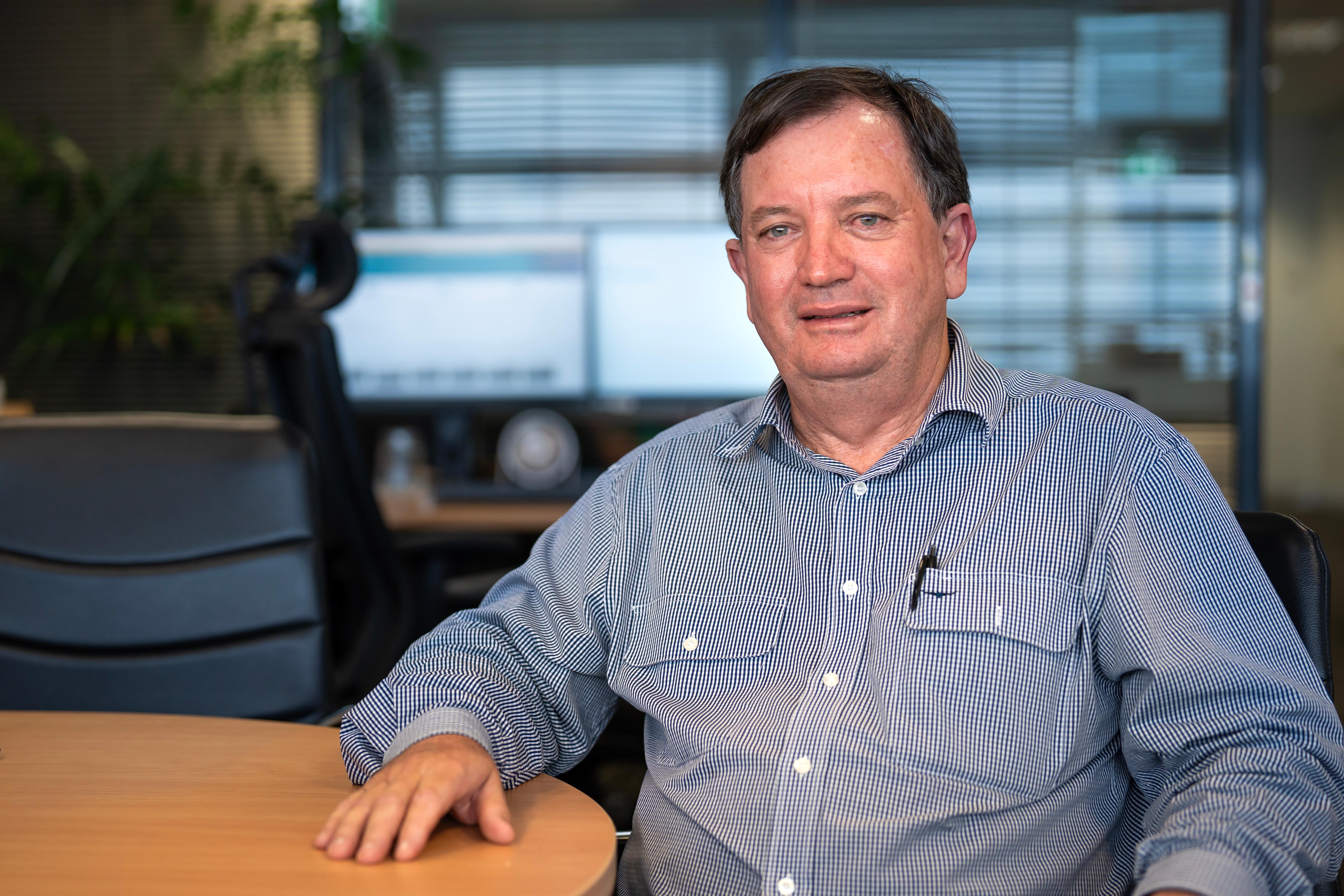 Um homem de camisa de colarinho azul está sentado à mesa.