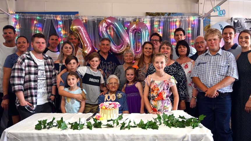 Four generations of the Seymour family stand behind Ivy, smiling in celebration of her 100th birthday.