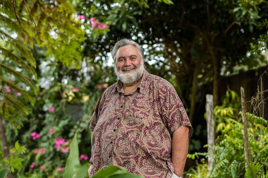 Man wearing colourful shirt stands in garden