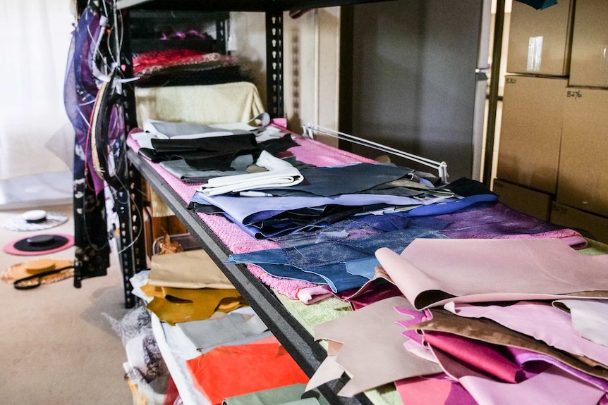 Piles of fabrics are shown on shelving.