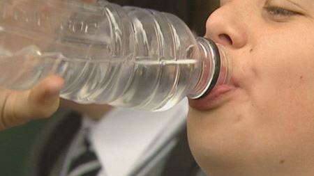 A kid drinking from a water bottle.