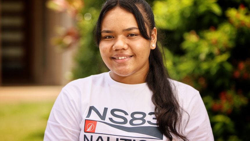 Young woman in a white shirt with her hair in a ponytail.