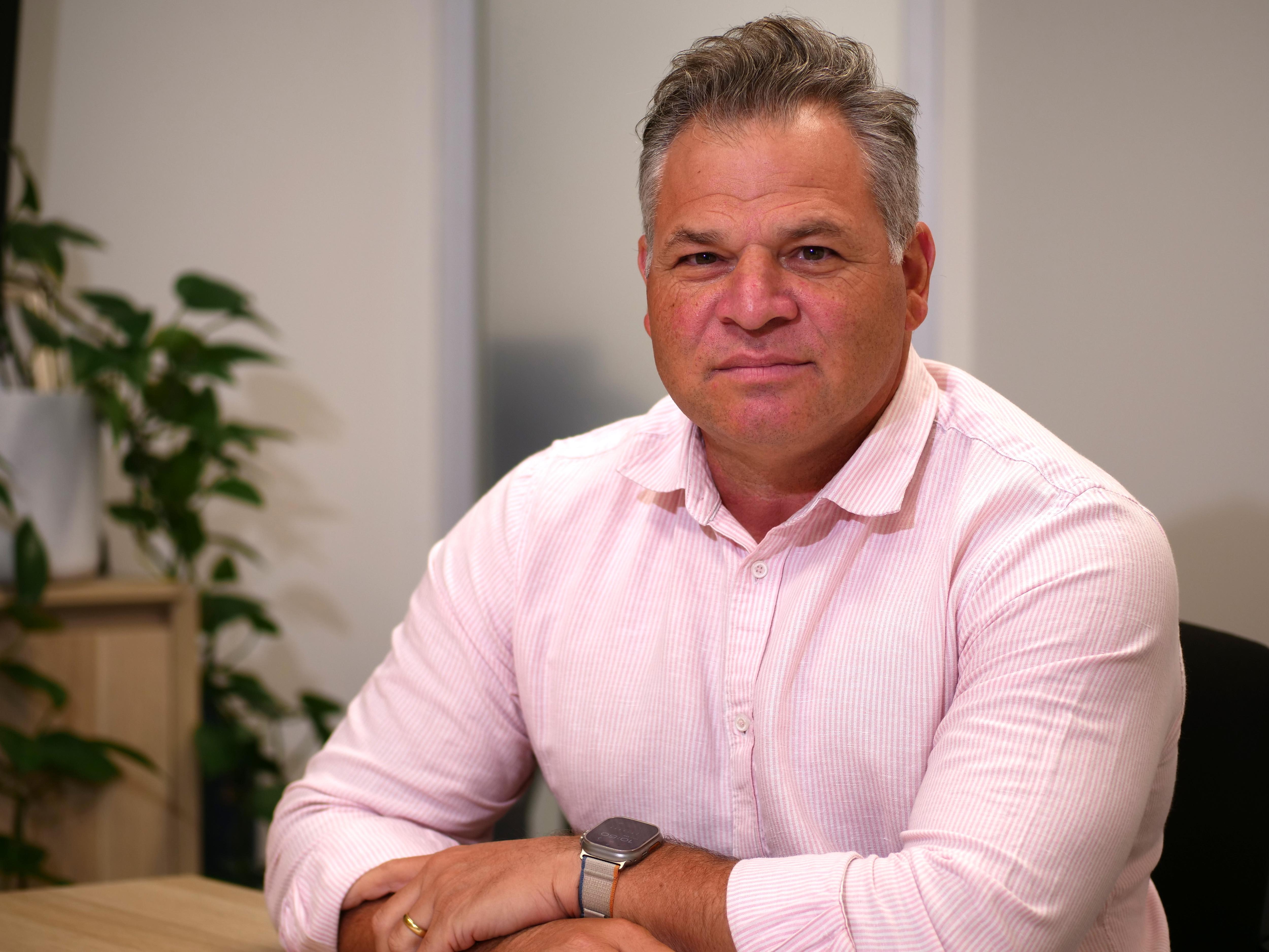 man in pink shirt sitting at desk 