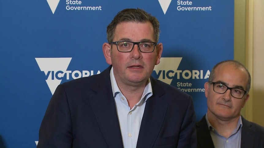 Dan Andrews speaks with James Merlino behind him in front of a Vic gov sign