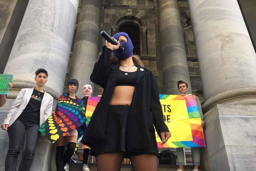 A masked member of Russian punk rock group Pussy Riot holds a microphone.