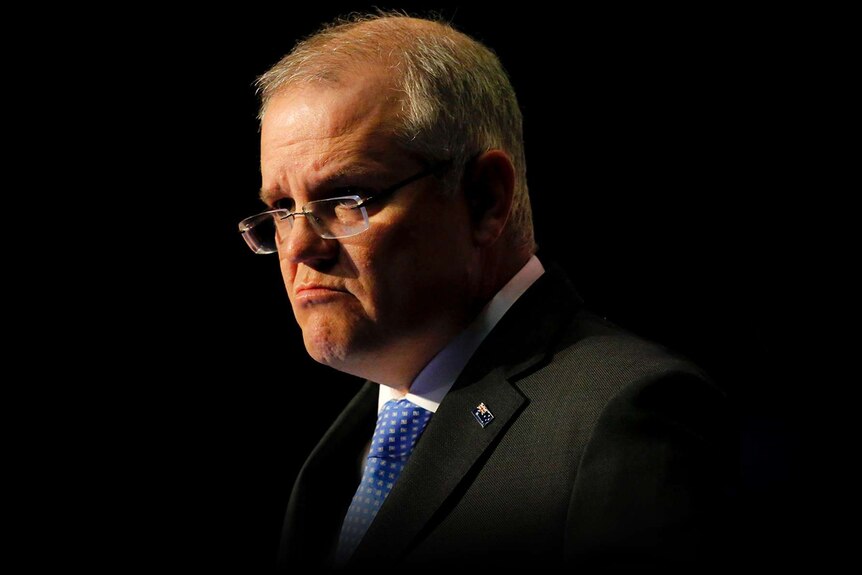 Scott Morrison frowns during a speech at Parliament House. The background is dark