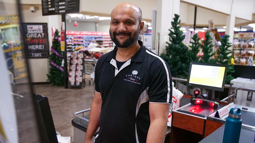 A man stands at a supermarket checkout.