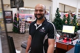 A man stands at a supermarket checkout.