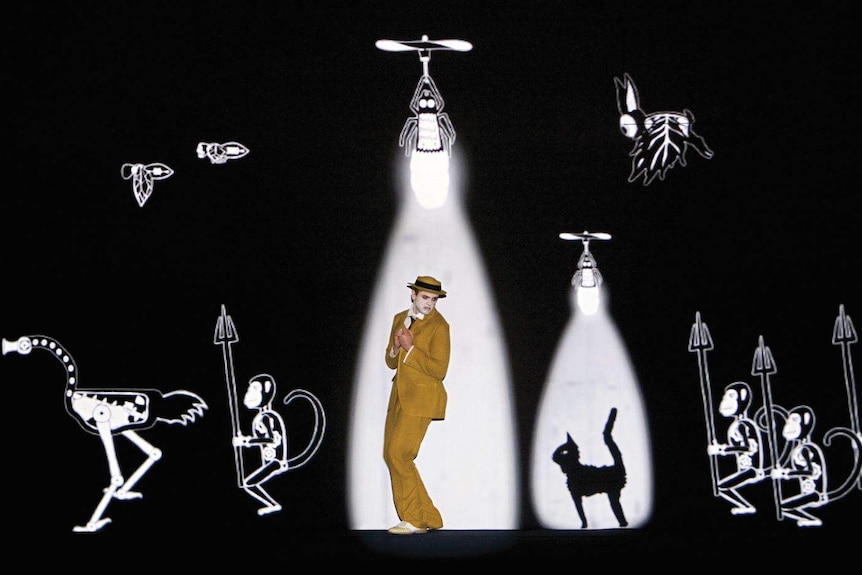 A man on a stage with projections of outlandish animals