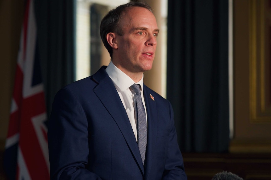 British Foreign Minister Dominic Raab wears a dark suit.