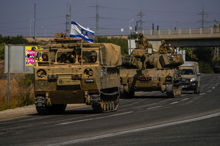 Israeli troops in tanks ride on highway road 
