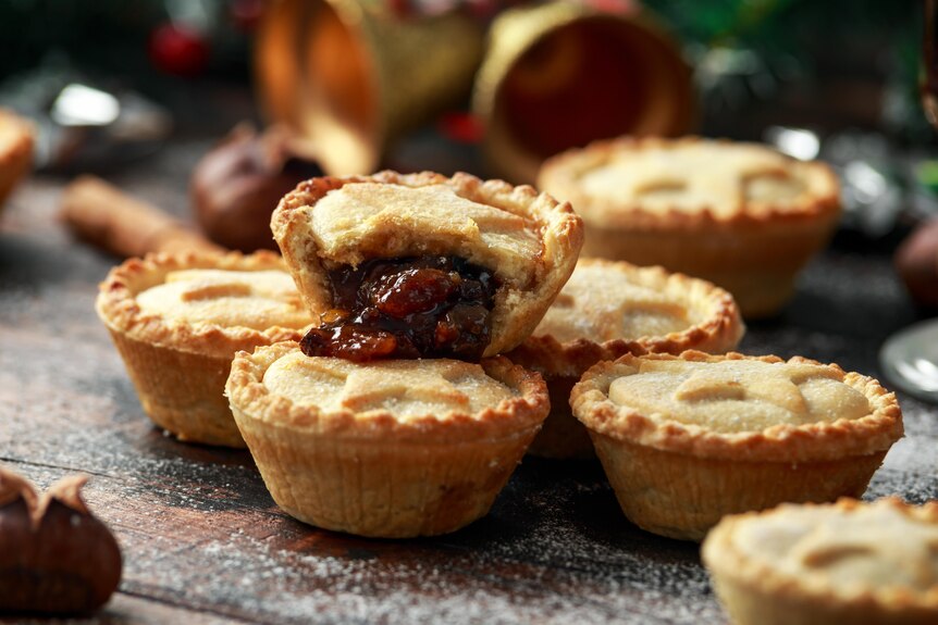 Fresh fruit mince pies resting on a wooden table.