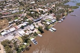 Aerial photo of houses and businesses next to a brown river.