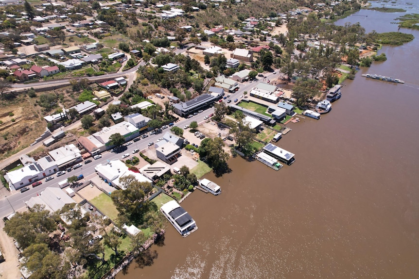 Aerial photo of houses and businesses next to a brown river.