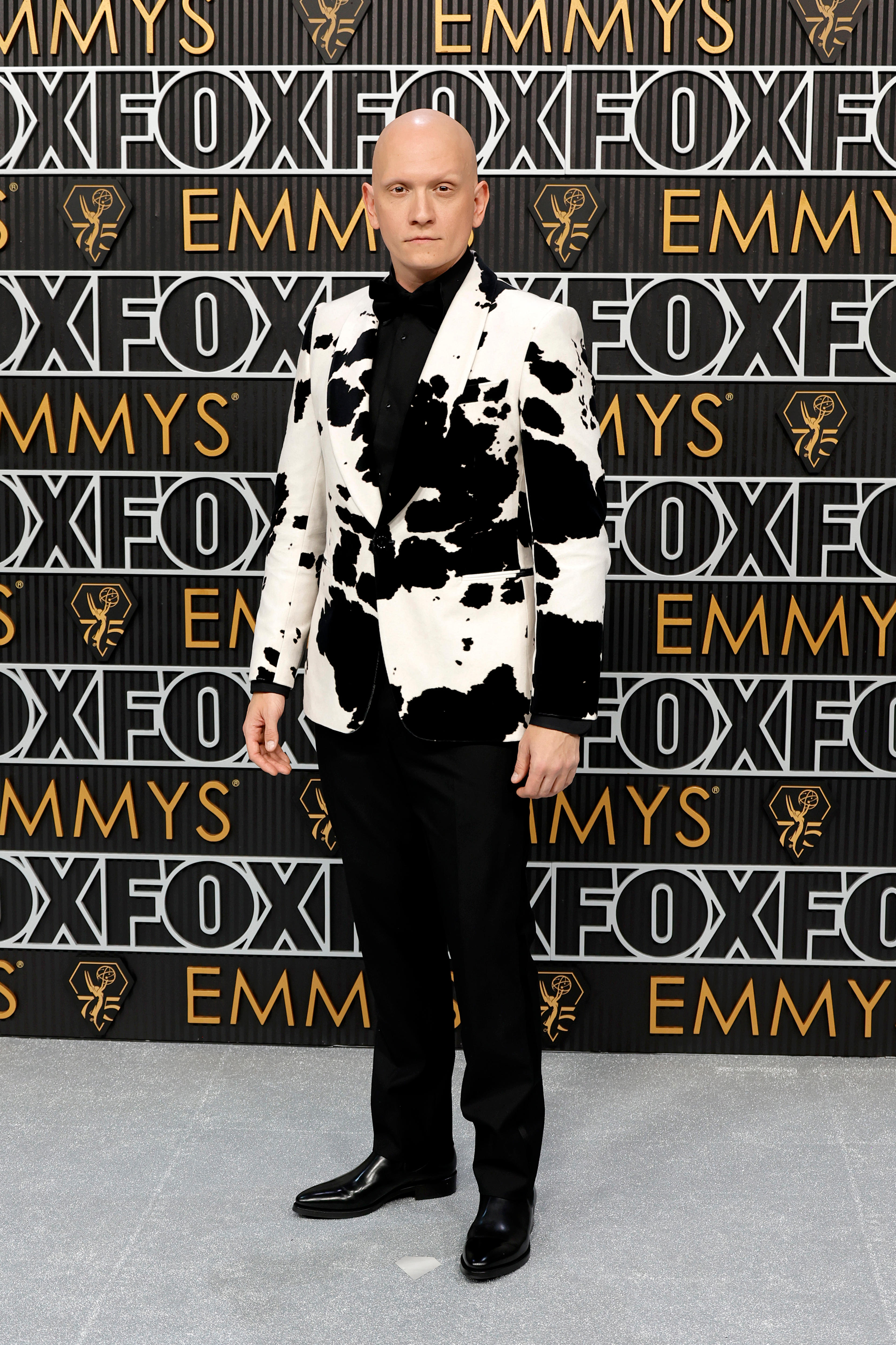 A man in a cowprint suit on a red carpet 