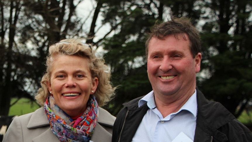 A woman and man standing next to each other with trees in the background