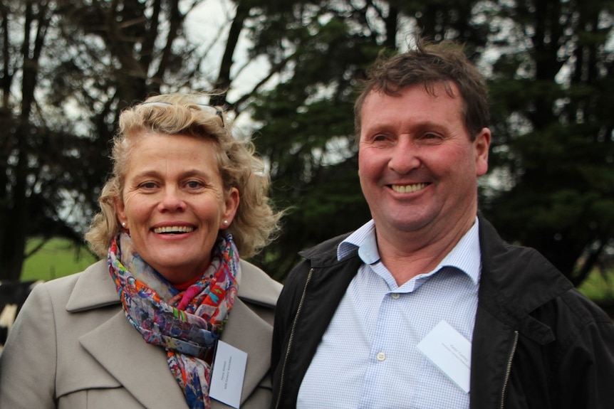 A woman and man standing next to each other with trees in the background