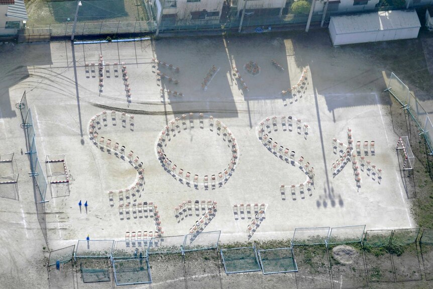 Aerial view of chairs spelling out "(Toilet) Paper, Bread, Water and SOS".