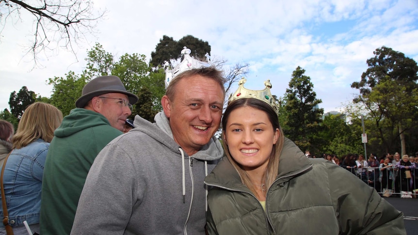A father and teenage daughter, both wearing toy crowns