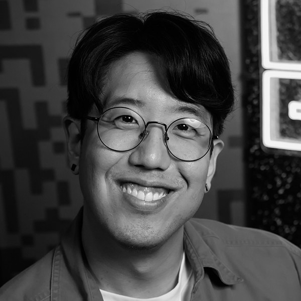 A man with short, wavy hair, glasses and a collared shirt smiles for the camera
