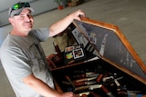Bundaberg knife maker Scott Simmonds stands beside an open case displaying his hand made knives