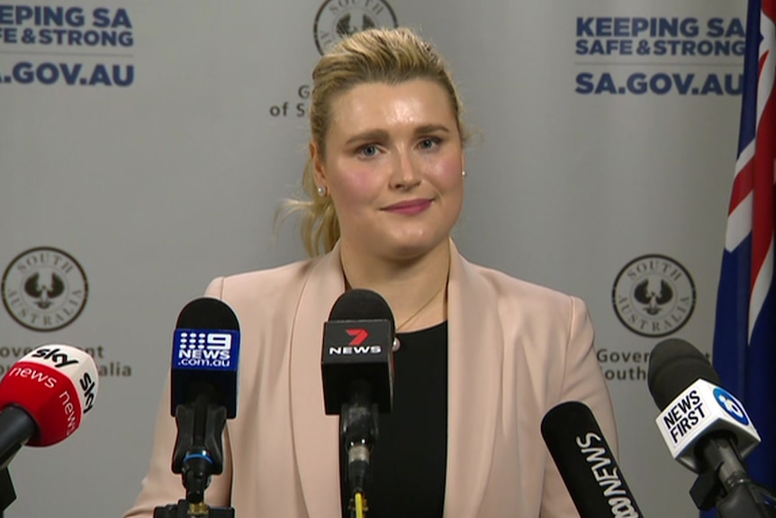 A woman with blonde hair wearing a peach-coloured blazer and a black shirt