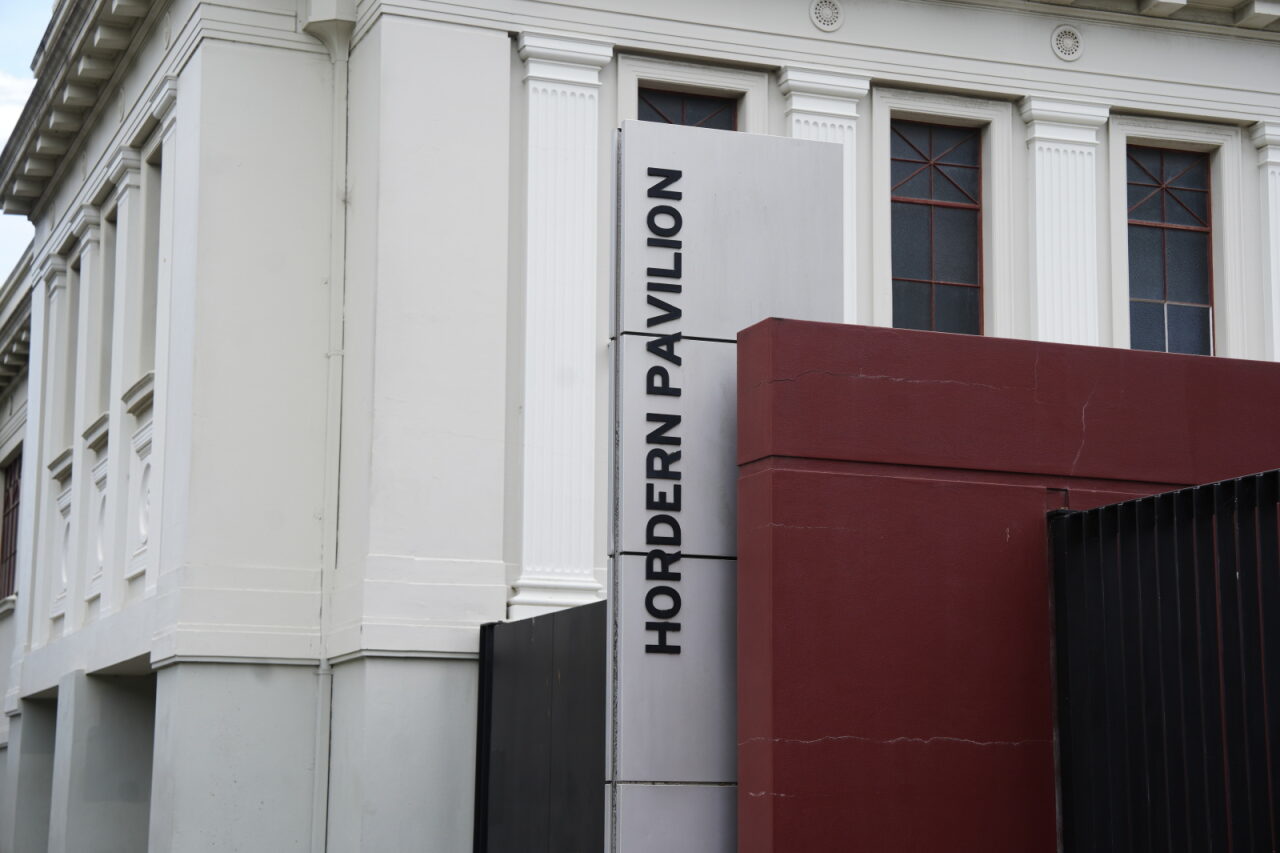 Exterior do edifício branco com sinalização.