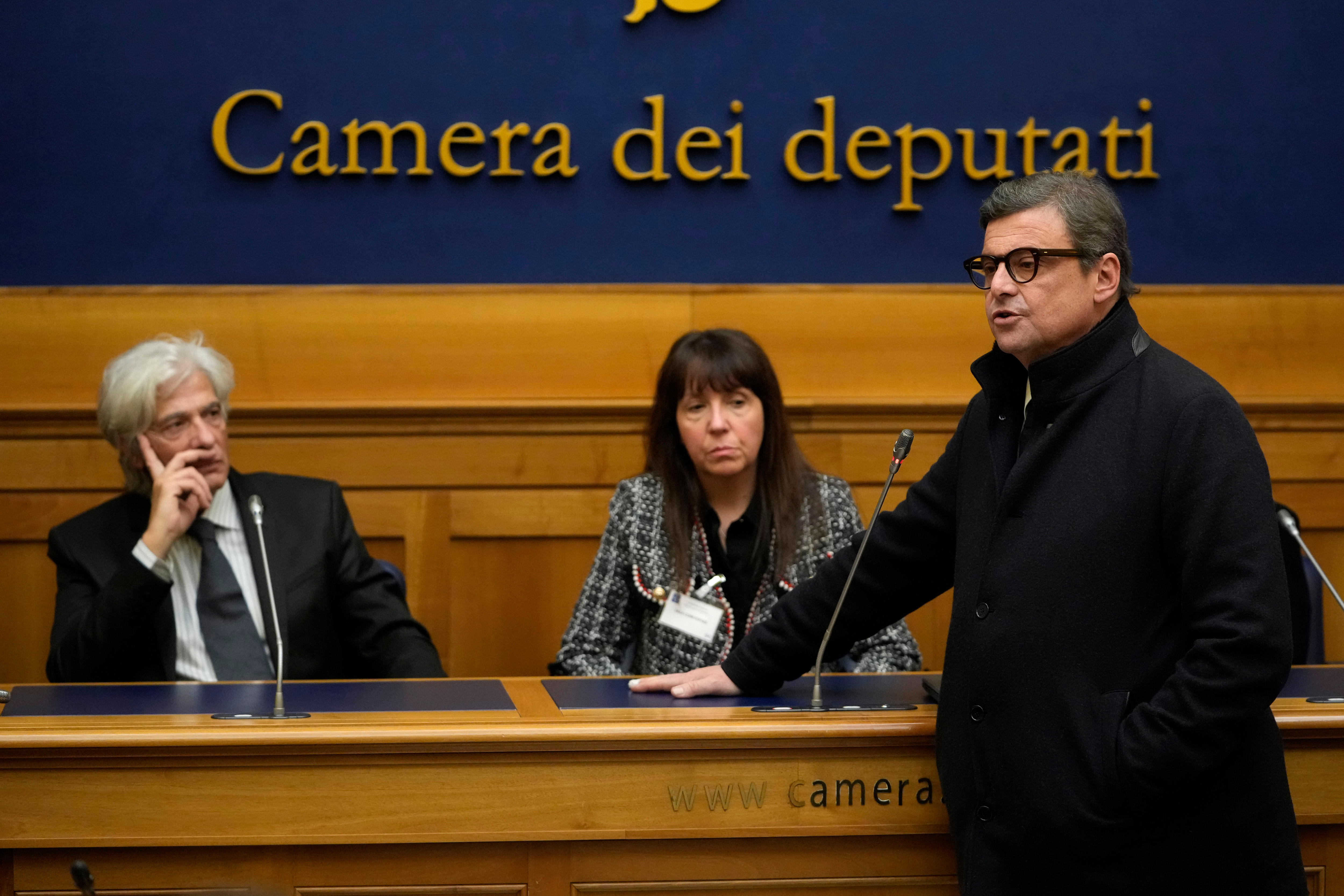 Senator Carlo Calenda stands at a parliamentary bench while  Pietro Orlandi and Maria Antonietta Gregori watch on. 