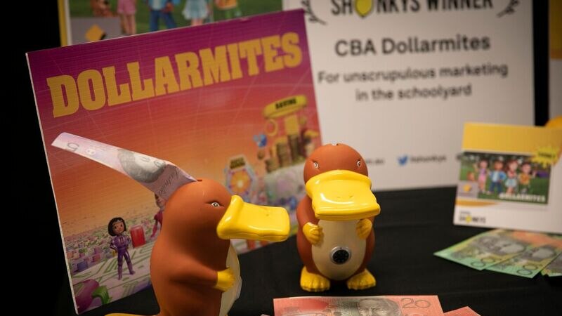 Two platypus moneyboxes with five, ten and twenty dollar notes around them and an award certificate in background.