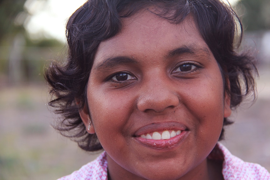 A young Aboriginal woman looks directly at the camera