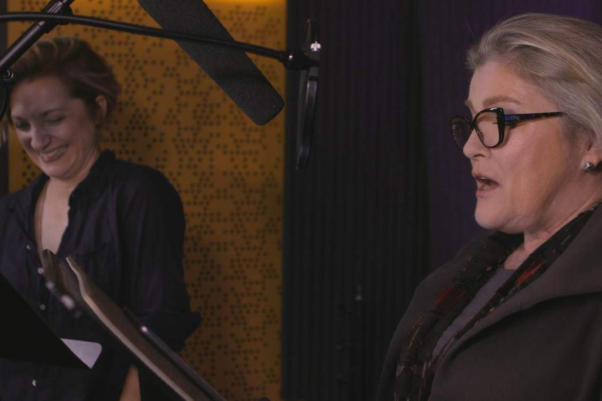 Francesca Faridany (left) and Kate Mulgrew (right) stand at microphones in a recording studio.