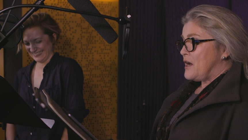 Francesca Faridany (left) and Kate Mulgrew (right) stand at microphones in a recording studio.