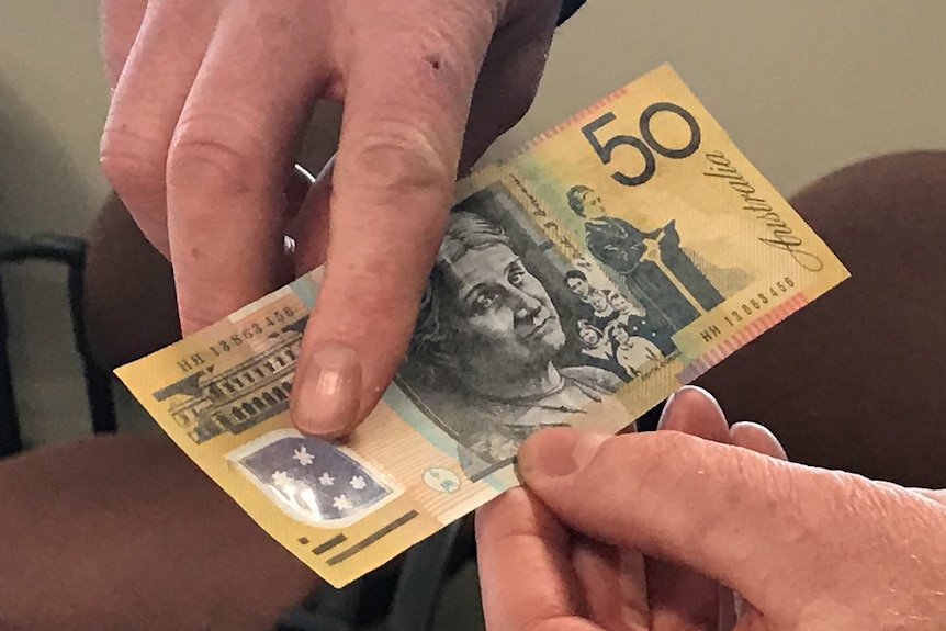 A Tasmania Police officer points out the features on a counterfeit $50 note
