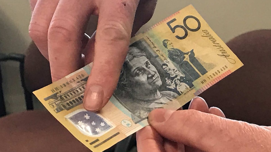 A Tasmania Police officer points out the features on a counterfeit $50 note