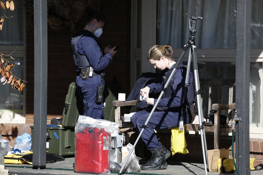 Police in forensic uniforms bag up evidence outside a home, including a petrol canister.