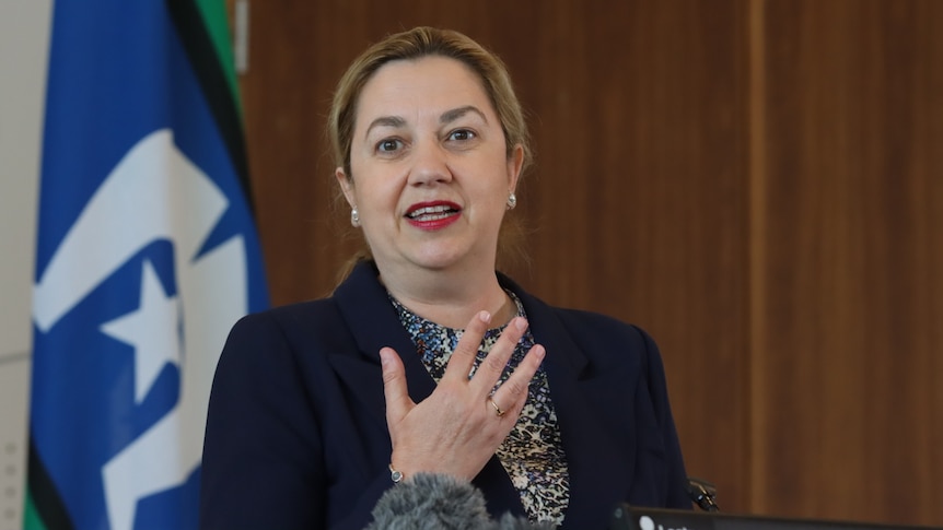 premier gesturing as she speaks, behind a lecturn 